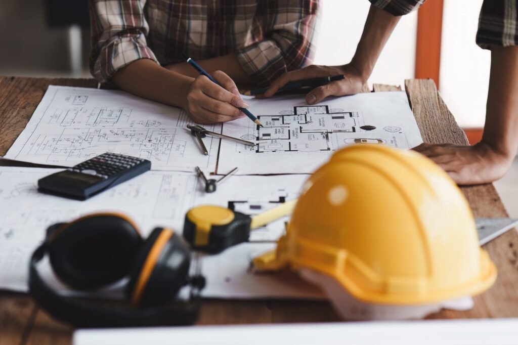 Architect and Engineer working with blueprints for architectural plan, engineer sketching a